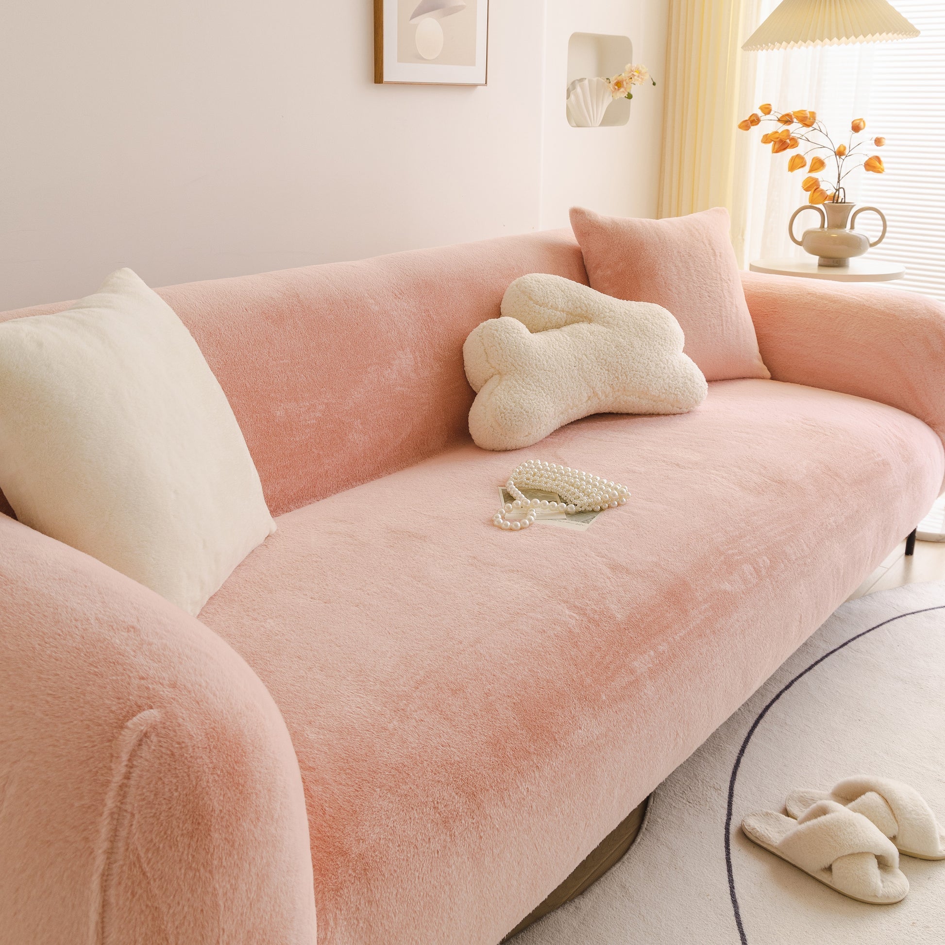 Pink sofa with decorative pillows and a small table in a bright room.