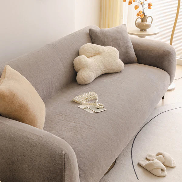 Gray sofa with decorative pillows and a teddy bear in a living room setting.